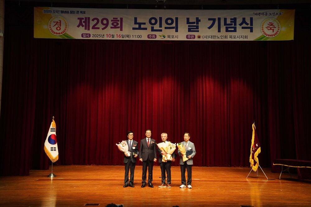 노인의 날 기념식에서 관계자와 수상자들이 꽃다발을 들고 단체 기념 촬영을 하고 있는 모습이다.