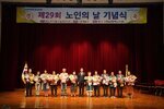 노인의 날 기념식에서 수상자들이 꽃다발을 들고 관계자와 함께 단체 기념 촬영을 하고 있는 모습이다.