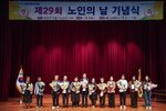 노인의 날 기념식에서 수상자들이 패와 꽃다발을 들고 단체 기념 촬영을 하고 있는 모습이다.